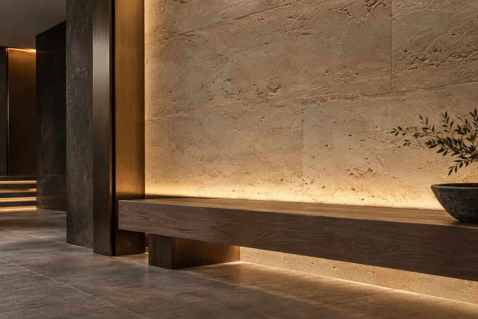 Concealed warm light brushes across textured limestone beside a timber bench.
